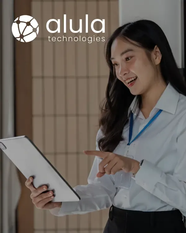 Alula Technologies logo over a professional presenting on a tablet