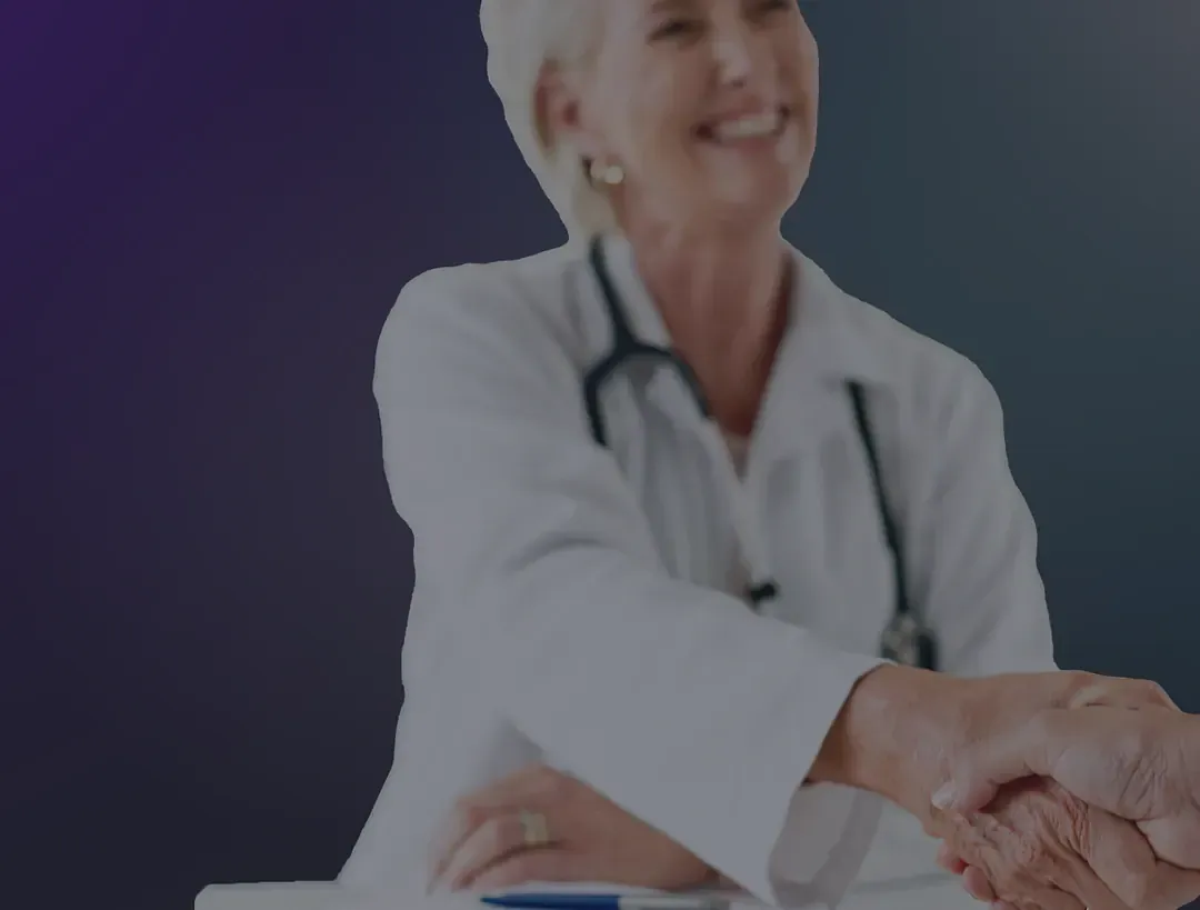 Smiling doctor shaking hands with a client across a desk